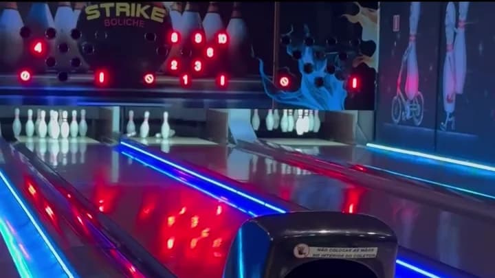 Pistas e pinos do Strike Boliche com iluminação azul e vermelha