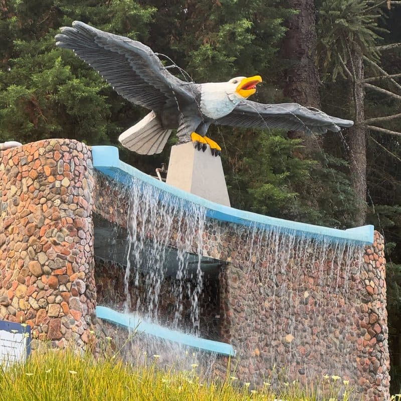 Escultura de águia sobre a cascata de pedra da rampa molhada