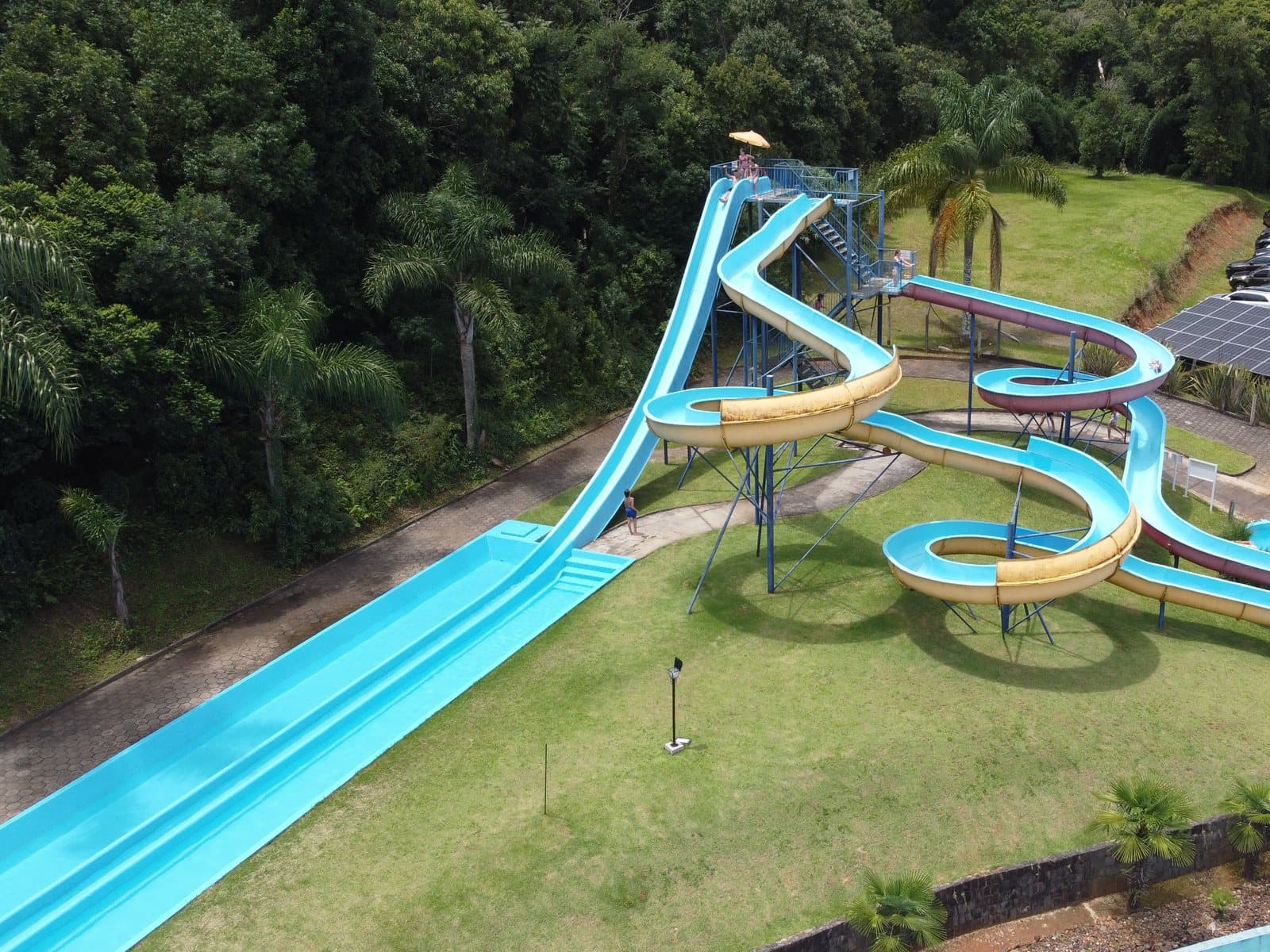 Vista aérea da torre de toboáguas em espiral, azul e amarela, ao lado do toboágua reto e da piscina
